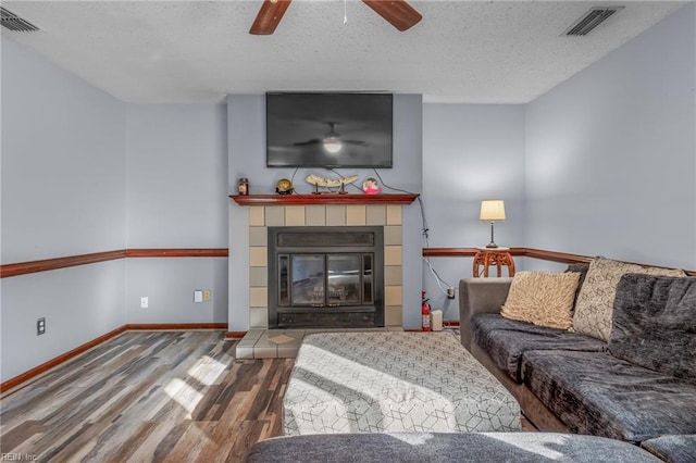 living area with visible vents, a fireplace, baseboards, and wood finished floors