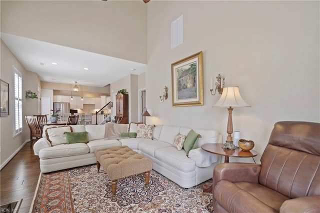 living room featuring recessed lighting, a high ceiling, wood finished floors, baseboards, and stairs