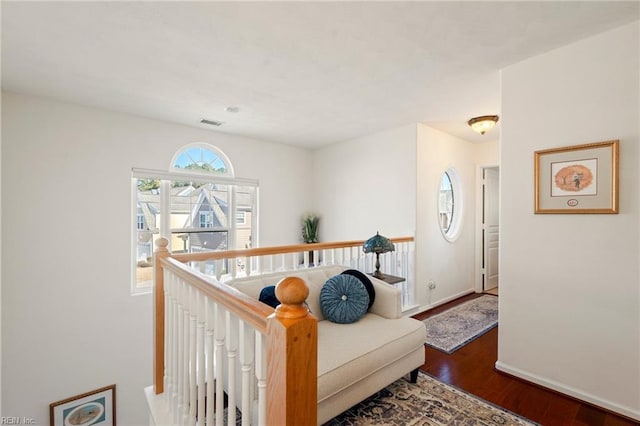 hall with an upstairs landing, wood finished floors, visible vents, and baseboards