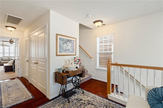 corridor featuring stairs, visible vents, baseboards, and wood finished floors