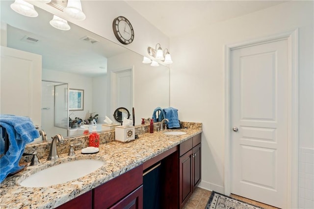 bathroom featuring double vanity, a stall shower, visible vents, and a sink