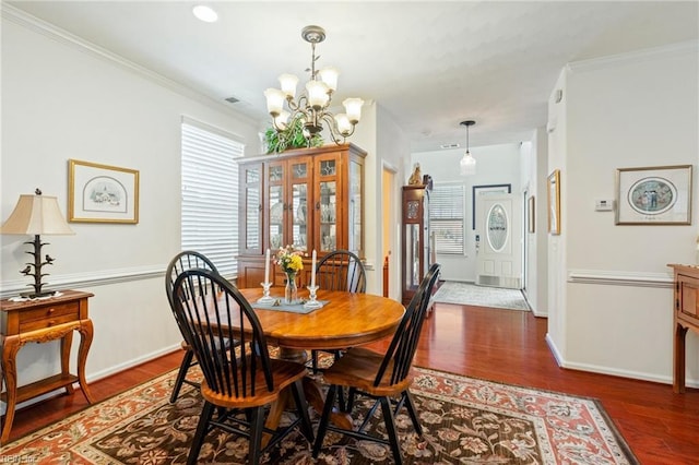 dining area with a notable chandelier, baseboards, wood finished floors, and crown molding