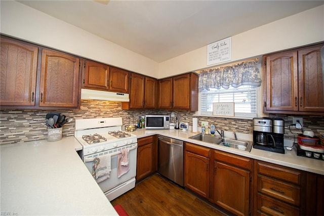 kitchen with light countertops, decorative backsplash, appliances with stainless steel finishes, a sink, and under cabinet range hood