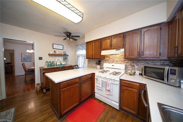 kitchen with light countertops, stainless steel microwave, a peninsula, white range with gas stovetop, and under cabinet range hood