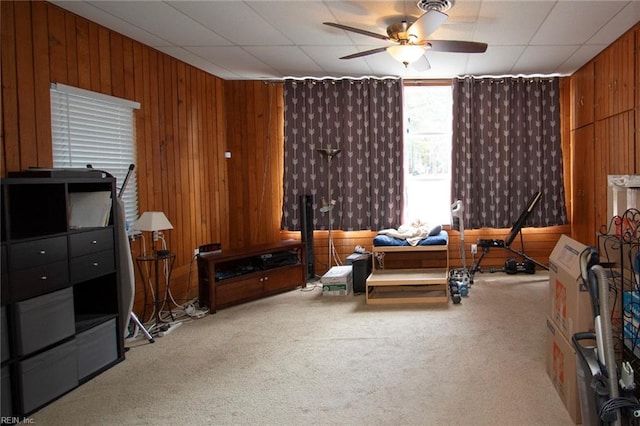 sitting room featuring ceiling fan, carpet flooring, and wooden walls