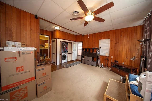 interior space with ceiling fan, wooden walls, visible vents, washer / clothes dryer, and carpet