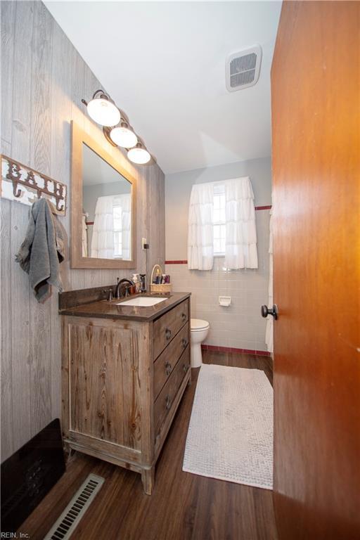 full bath with visible vents, vanity, toilet, and wood finished floors