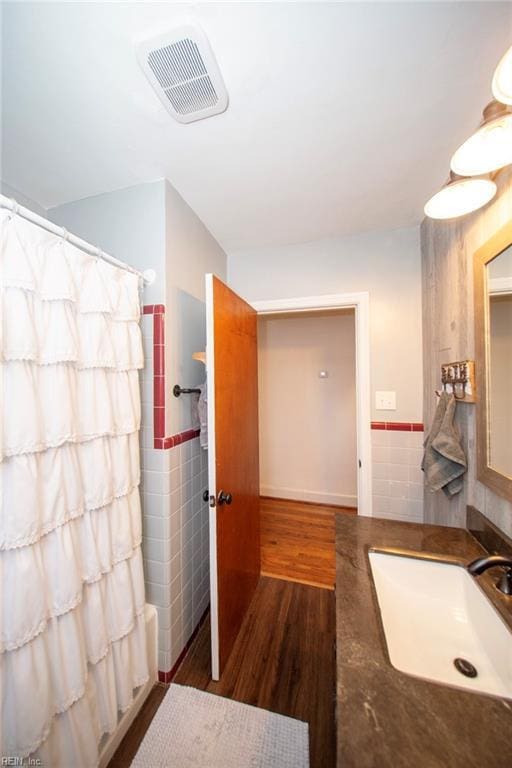 full bath featuring wood finished floors, vanity, visible vents, tile walls, and shower / bath combination with curtain