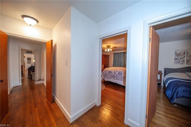 hall with baseboards and wood finished floors