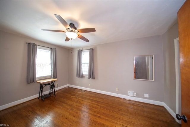 empty room featuring a ceiling fan, baseboards, and wood finished floors