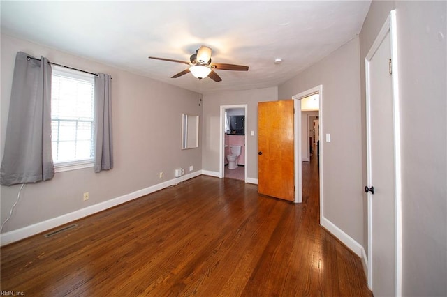 unfurnished bedroom featuring baseboards, visible vents, a ceiling fan, ensuite bath, and wood finished floors