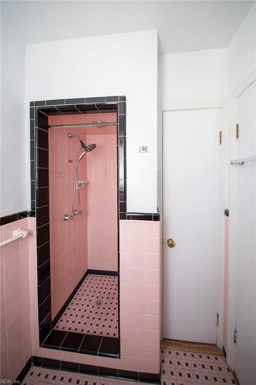 bathroom featuring a wainscoted wall, a shower stall, and tile walls