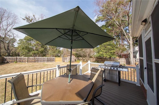 deck featuring a fenced backyard, a grill, outdoor dining area, and a lawn