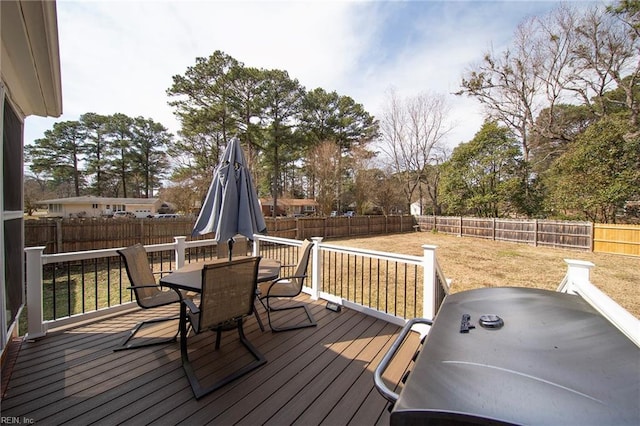 wooden terrace with a fenced backyard, a grill, outdoor dining area, and a lawn