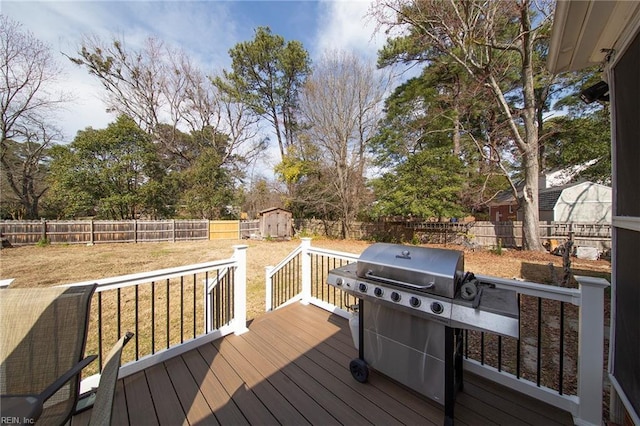 wooden deck featuring a fenced backyard, area for grilling, an outdoor structure, a yard, and a shed