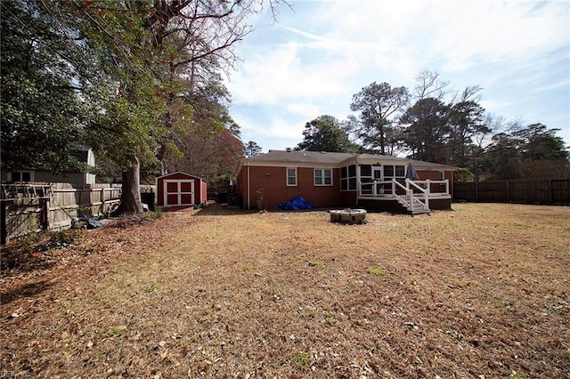 back of house featuring an outdoor fire pit, a storage unit, a fenced backyard, and an outbuilding