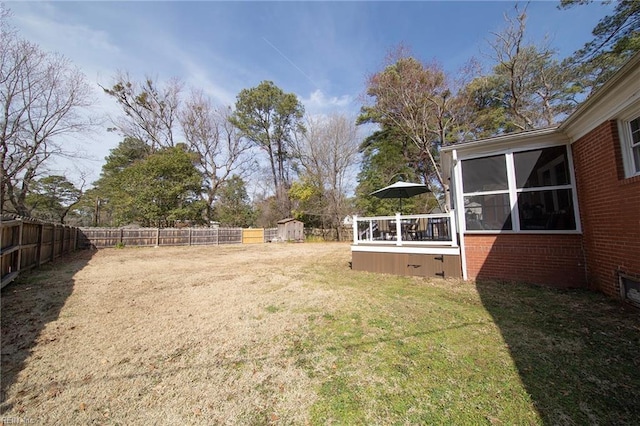 view of yard with a storage shed, a fenced backyard, a sunroom, and an outdoor structure