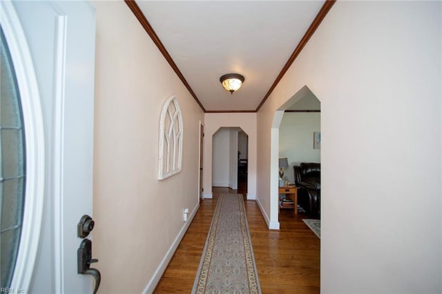 hallway with arched walkways, crown molding, light wood-type flooring, and baseboards