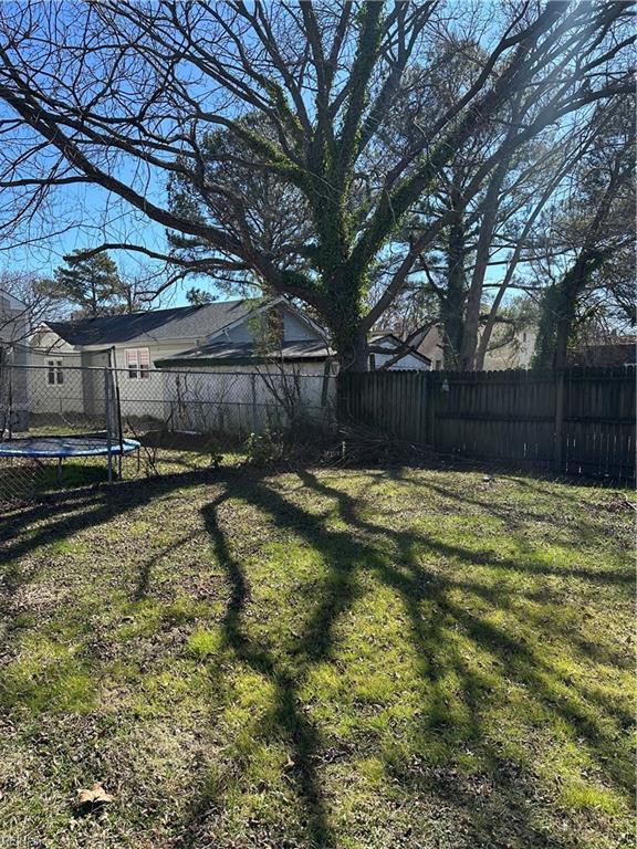 view of yard featuring a trampoline and a fenced backyard