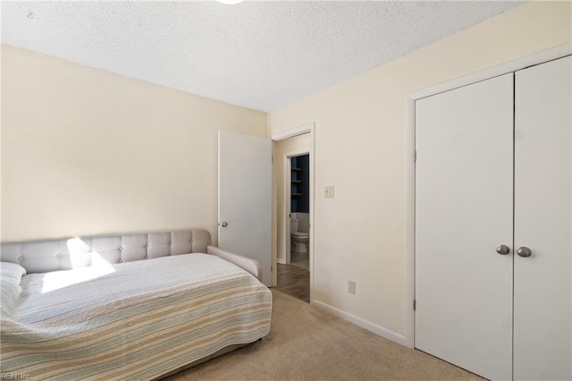 carpeted bedroom featuring a textured ceiling, a closet, and baseboards