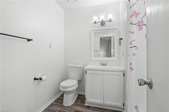 bathroom featuring baseboards, vanity, toilet, and wood tiled floor