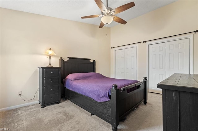 bedroom with a ceiling fan, carpet, baseboards, and two closets