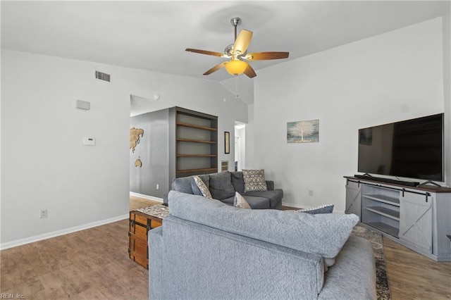 living area featuring wood finished floors, visible vents, baseboards, vaulted ceiling, and a ceiling fan