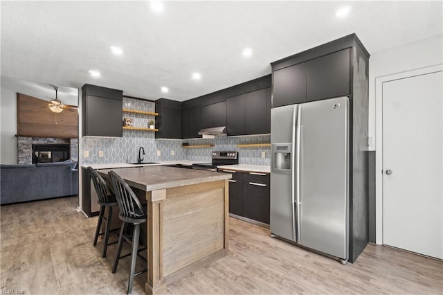 kitchen with open shelves, under cabinet range hood, stainless steel appliances, and light wood finished floors