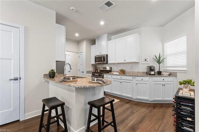 kitchen with visible vents, white cabinets, dark wood-style floors, stainless steel appliances, and a sink