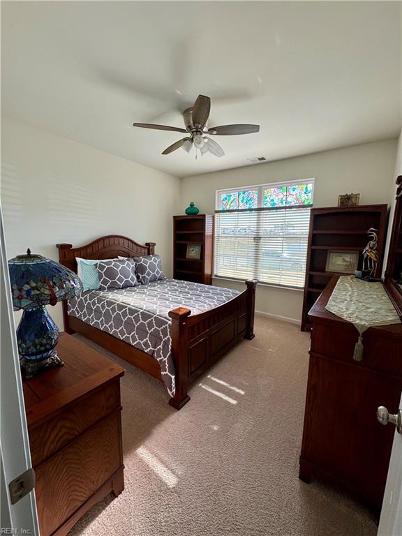 bedroom with ceiling fan, visible vents, baseboards, and light colored carpet