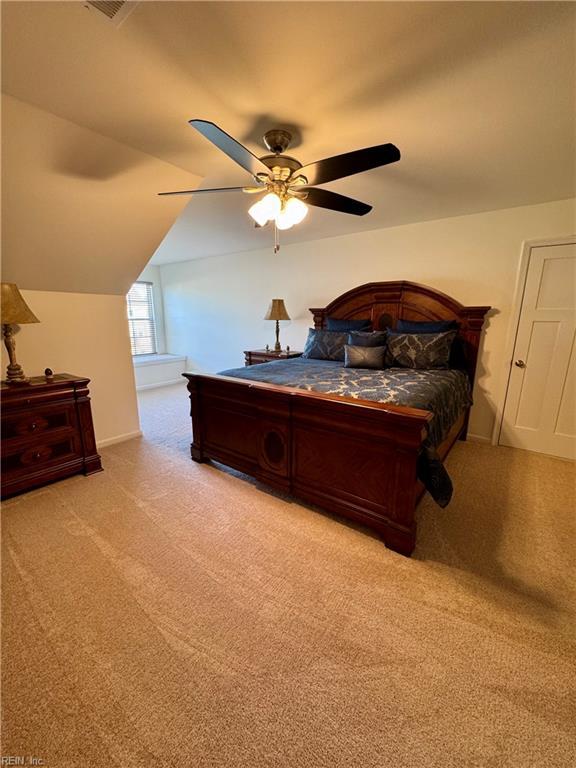 bedroom with a ceiling fan, light colored carpet, and vaulted ceiling