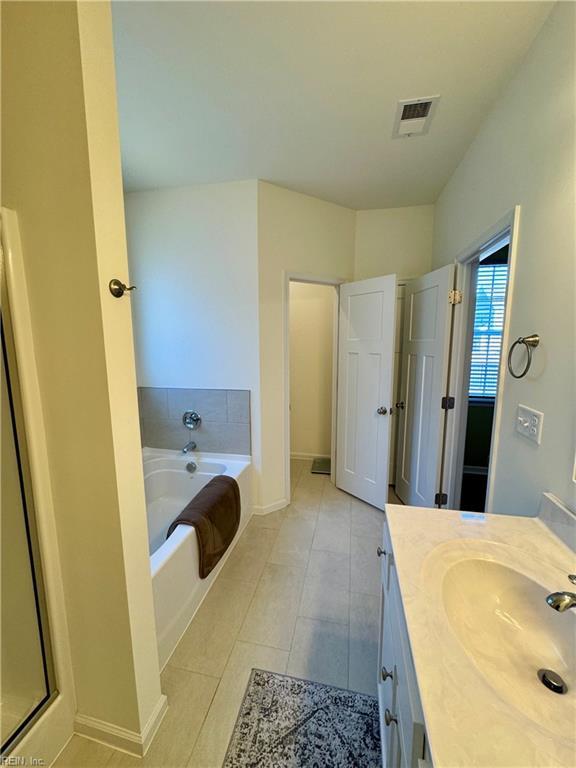 bathroom with a garden tub, visible vents, vanity, tile patterned flooring, and baseboards