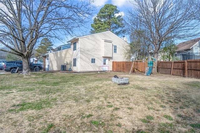 exterior space featuring a playground, a yard, a chimney, central AC, and fence