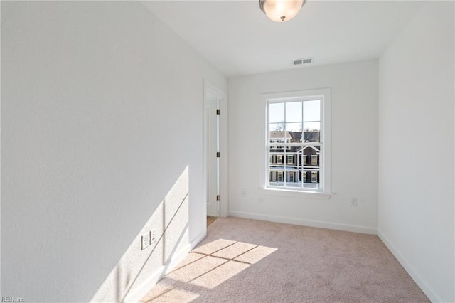 spare room featuring light carpet, visible vents, and baseboards