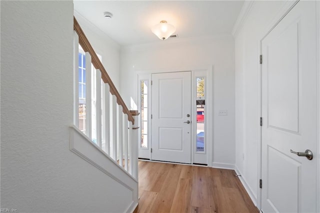 foyer entrance with stairs, baseboards, light wood-style flooring, and crown molding