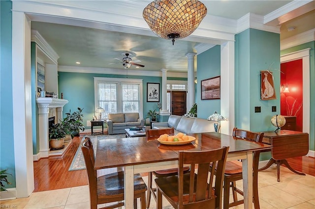dining space with crown molding, decorative columns, ceiling fan, and light tile patterned floors