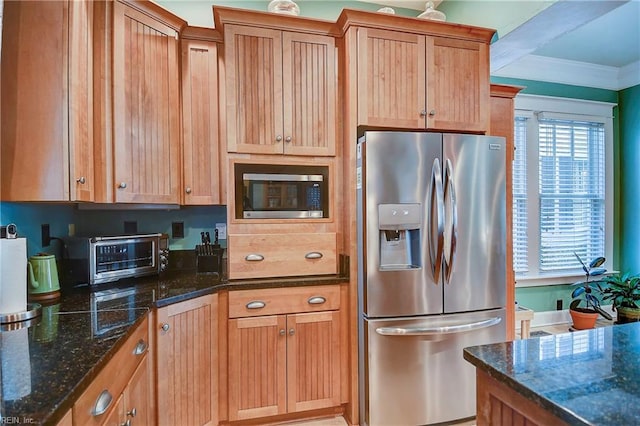 kitchen featuring crown molding, stainless steel appliances, dark stone countertops, and a toaster
