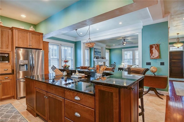 kitchen featuring decorative light fixtures, crown molding, light tile patterned floors, appliances with stainless steel finishes, and dark stone countertops