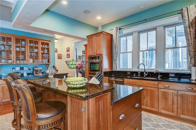kitchen with a sink, a kitchen island, appliances with stainless steel finishes, dark stone counters, and glass insert cabinets