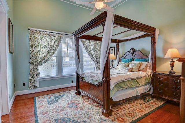 bedroom with ceiling fan, wood finished floors, and baseboards