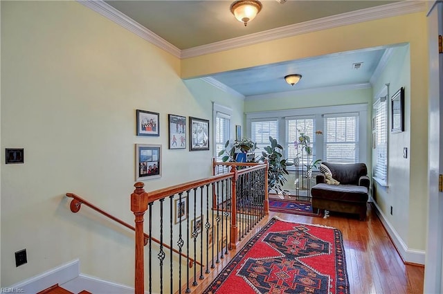 hallway with ornamental molding, baseboards, an upstairs landing, and wood finished floors