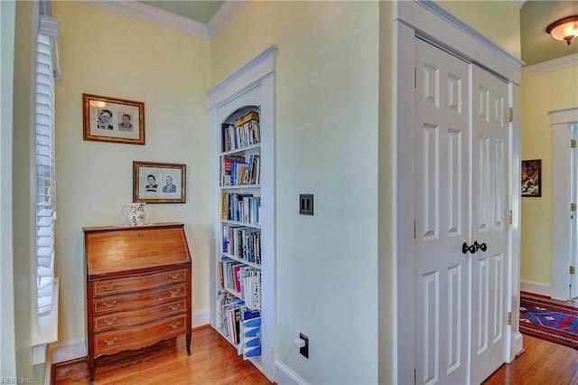 hallway with crown molding, baseboards, and wood finished floors