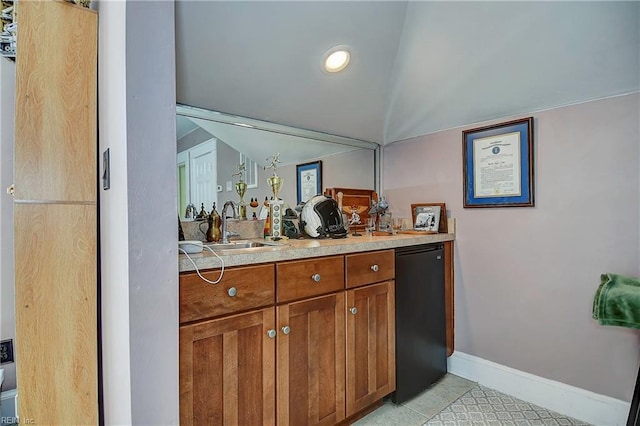 bar featuring refrigerator, a sink, lofted ceiling, and baseboards