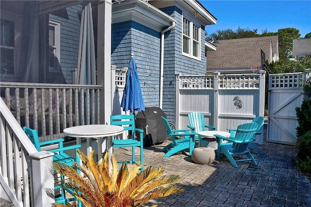 view of patio / terrace featuring fence, a gate, and a grill