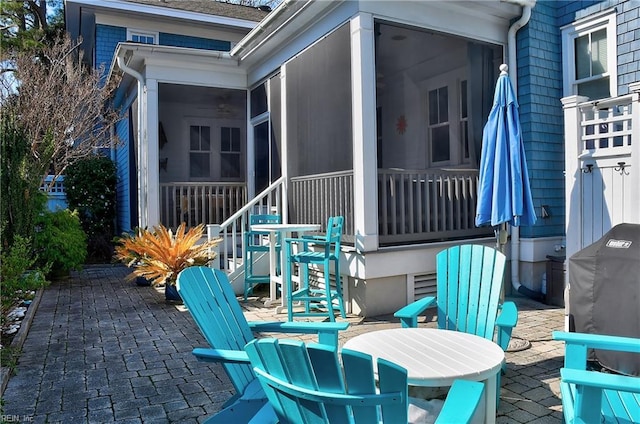 view of patio with a sunroom and outdoor dining space