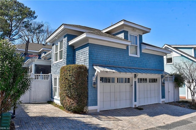 view of front of home with decorative driveway, a standing seam roof, metal roof, and an attached garage