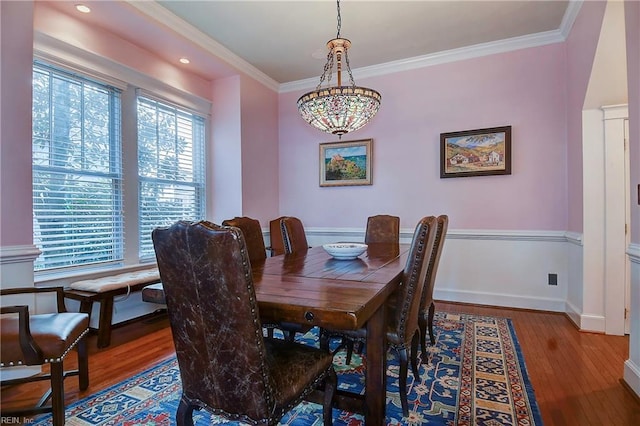 dining space with baseboards, wood finished floors, and crown molding