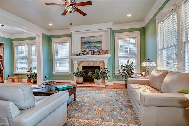 living area featuring a healthy amount of sunlight, a premium fireplace, and ornamental molding