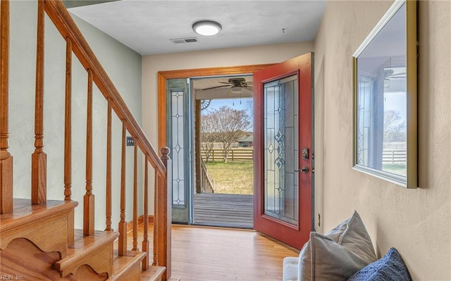 foyer entrance featuring stairs, visible vents, and wood finished floors