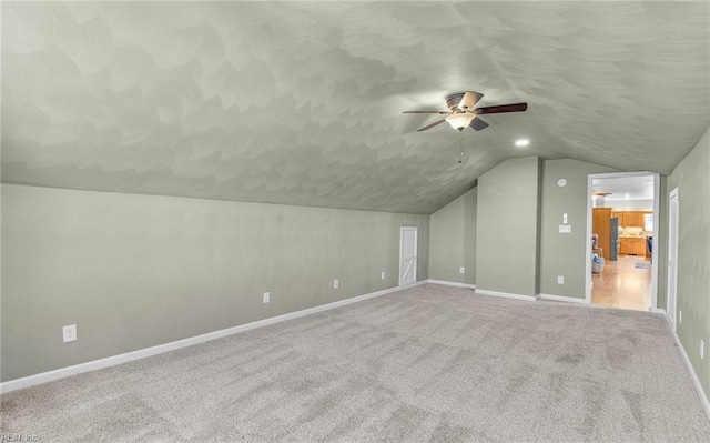 additional living space with lofted ceiling, ceiling fan, a textured ceiling, carpet floors, and baseboards